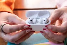 Hands holding open AirPods Pro case with earbuds inside.