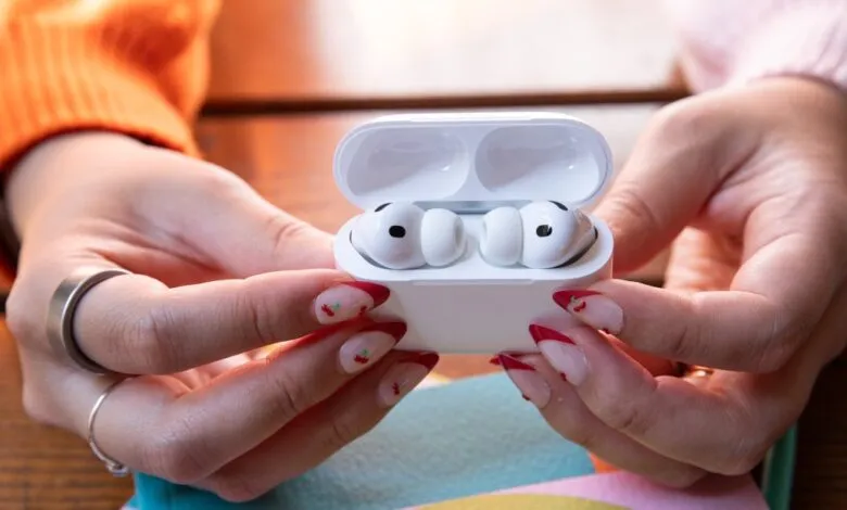 Hands holding open AirPods Pro case with earbuds inside.