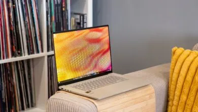 Laptop on a couch with a colorful screen and records in the background.