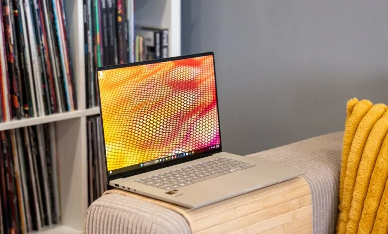 Laptop on a couch with a colorful screen and records in the background.