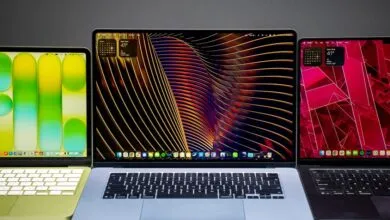 Three Apple MacBooks with different colored cases and screen wallpapers.