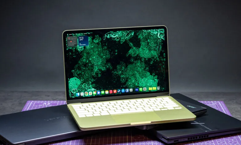 MacBook on top of Lenovo and Acer laptops, showcasing tech comparison.