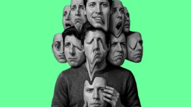Person holding mask with multiple distorted faces on a green background.