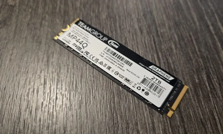 Teamgroup MP44Q 2TB NVMe SSD on a wooden surface.