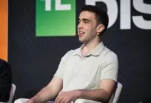 Man with curly hair wearing a light polo shirt and headset microphone.
