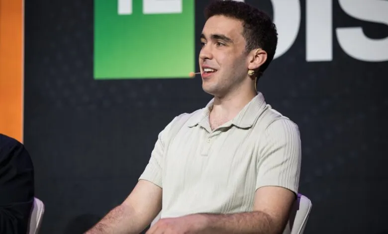 Man with curly hair wearing a light polo shirt and headset microphone.