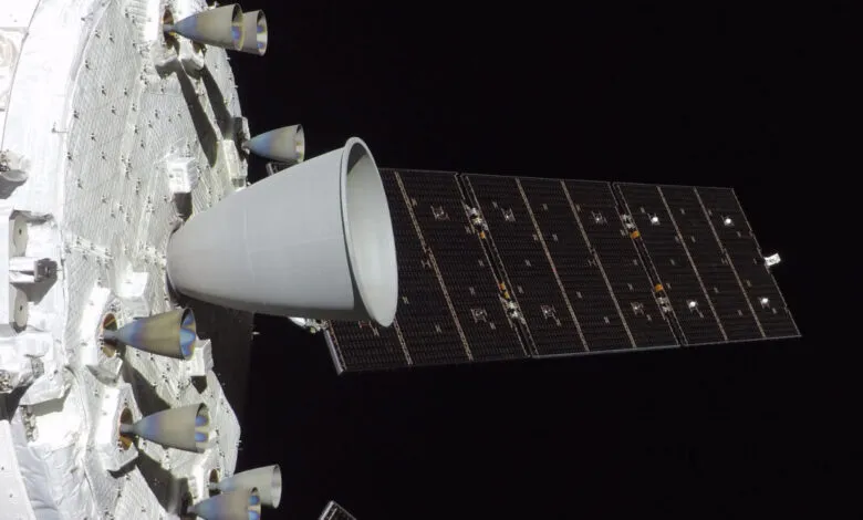Orion spacecraft with solar array and engines against black space.