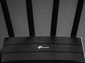 Black TP-Link router with four antennas on a dark background.