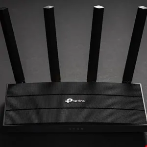 Black TP-Link router with four antennas on a dark background.