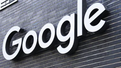 Google logo sign on a dark brick building exterior.