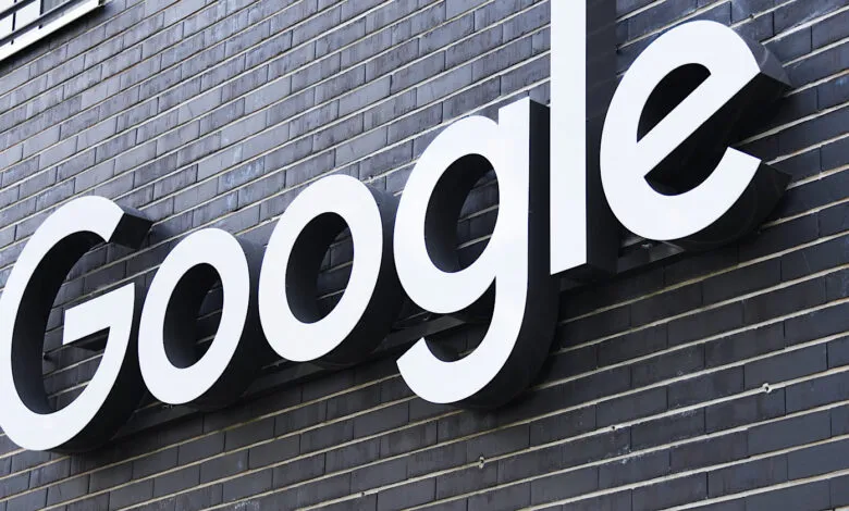 Google logo sign on a dark brick building exterior.