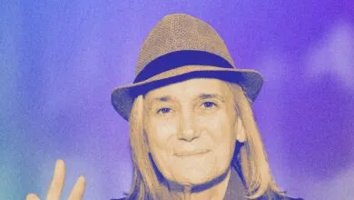 Amy Goodman, journalist, wearing a hat and making a peace sign.
