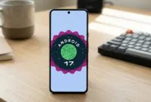 Smartphone displaying Android 17 logo on a wooden desk.