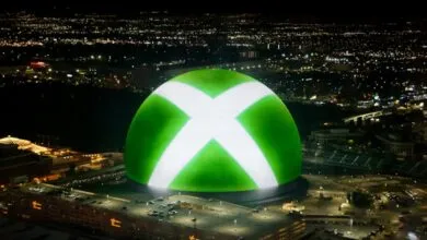 Large Xbox logo projected onto building at night, city lights in background.