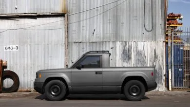 Gray pickup truck parked against corrugated metal wall.