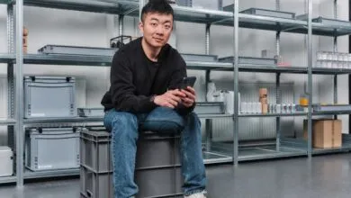 Carl Pei, CEO of Nothing, sits on a crate holding a phone.