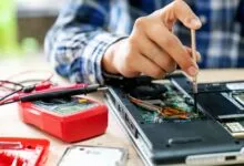 Laptop repair: technician uses screwdriver on open device.