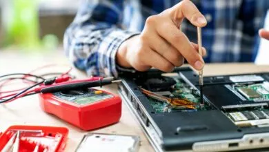 Laptop repair: technician uses screwdriver on open device.