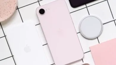 Pink iPhone SE with MagSafe charger on a grid background.