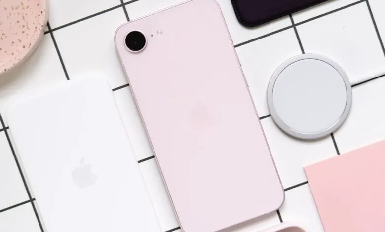 Pink iPhone SE with MagSafe charger on a grid background.