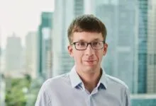 Headshot of Matei Zaharia, co-founder of Databricks, wearing glasses and a light blue shirt.