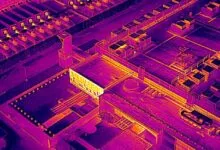 Aerial view of industrial complex in thermal imaging, showing heat signatures.