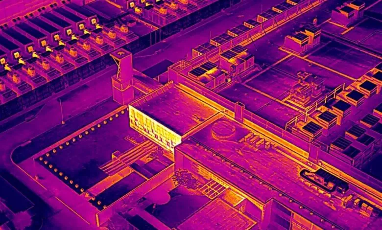 Aerial view of industrial complex in thermal imaging, showing heat signatures.