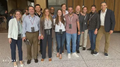 Group of diverse professionals posing indoors, wearing conference badges.
