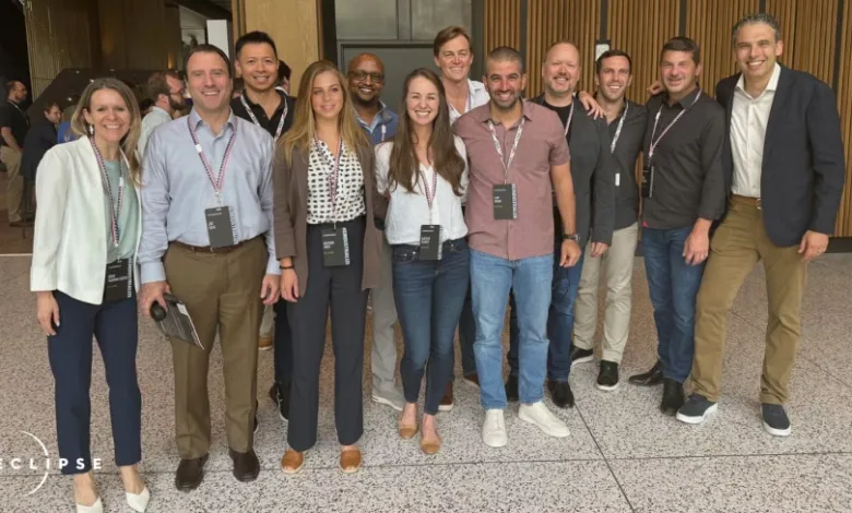 Group of diverse professionals posing indoors, wearing conference badges.