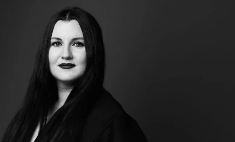 Black and white portrait of a woman with long dark hair and dark lipstick.