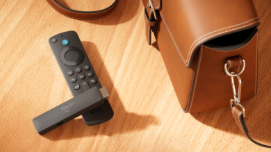 Amazon Fire TV Stick and remote on a wooden surface with a brown leather bag.