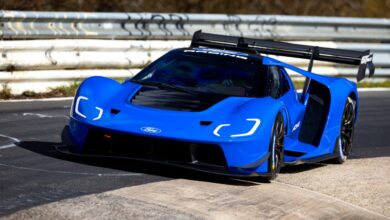 Bright blue Ford GT race car on a track with white barriers.