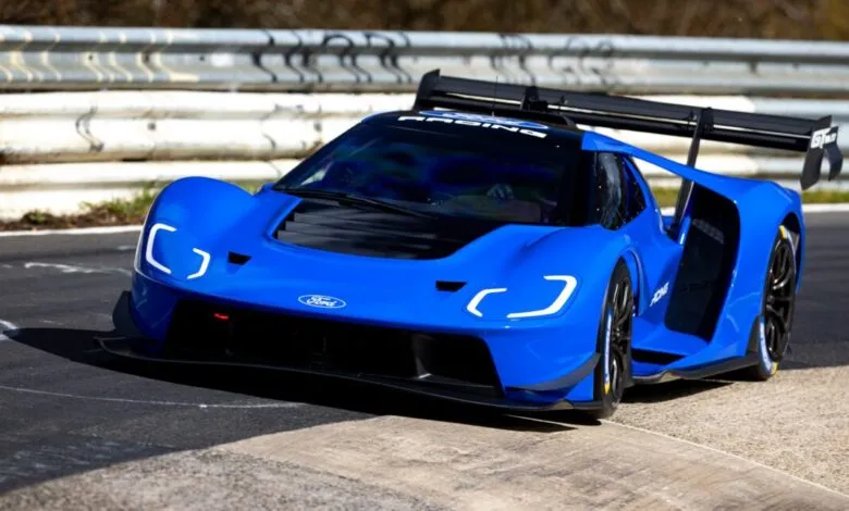 Bright blue Ford GT race car on a track with white barriers.