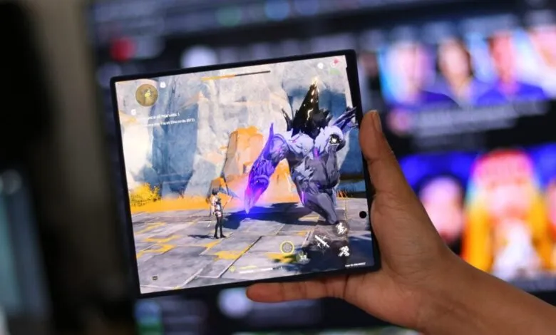 Foldable phone displays Genshin Impact gameplay in hand.