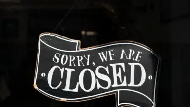 Black 'Sorry, We Are Closed' sign hangs in a shop window.