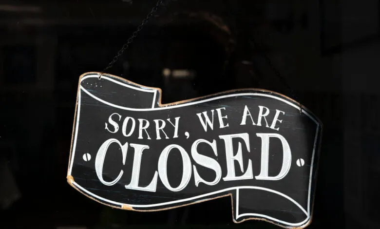 Black 'Sorry, We Are Closed' sign hangs in a shop window.