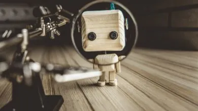 Wooden robot toy viewed through a magnifying glass on a wooden surface.