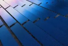 Aerial view of rows of blue solar panels in a field.