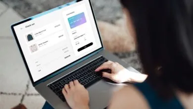 Woman types card details on laptop for online shopping checkout.