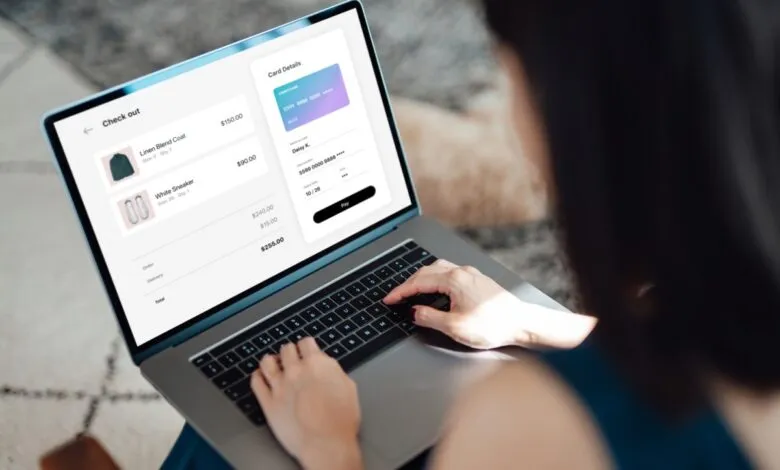 Woman types card details on laptop for online shopping checkout.