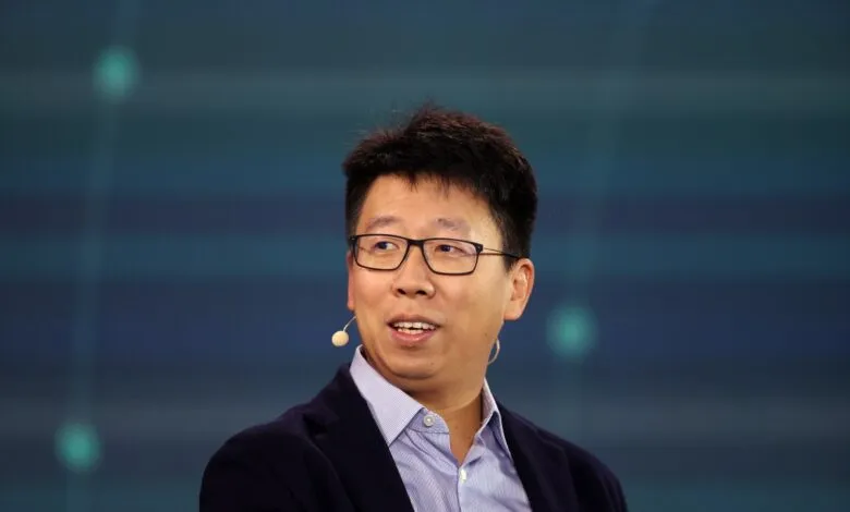 Portrait of a man with glasses and a microphone on a blue background.