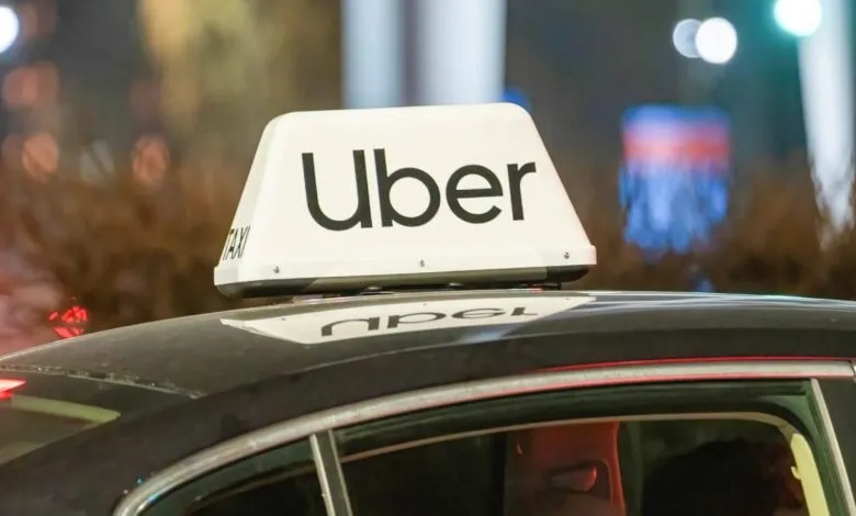 Uber car with illuminated sign on roof at night.