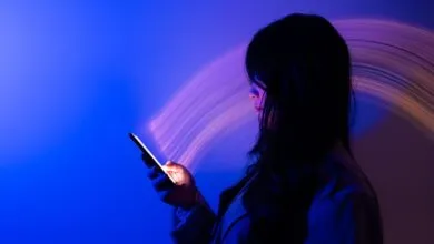Woman illuminated by phone screen in blue and purple light.