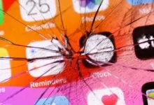 Cracked iPhone screen displaying app icons like Calendar, Clock, and TV.