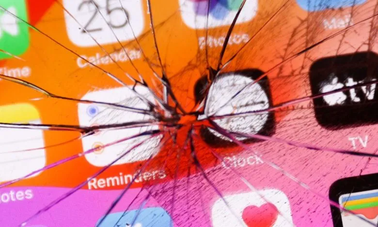 Cracked iPhone screen displaying app icons like Calendar, Clock, and TV.
