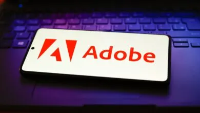 Adobe logo displayed on a smartphone screen resting on a laptop keyboard.