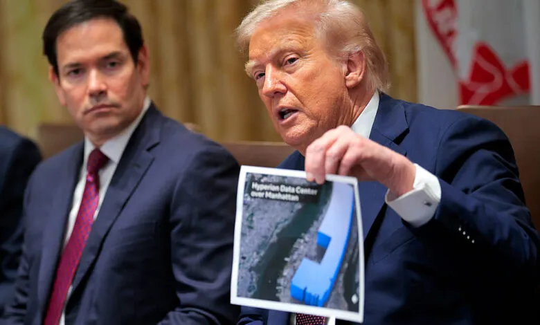 Donald Trump holds up a photo of a data center, Marco Rubio sits nearby.