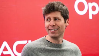 Sam Altman smiles against a red OpenAI backdrop.