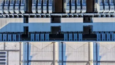 Aerial view of a large industrial building with rows of cooling units and concrete roof.