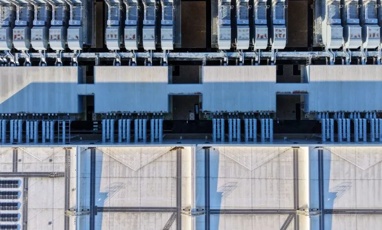 Aerial view of a large industrial building with rows of cooling units and concrete roof.